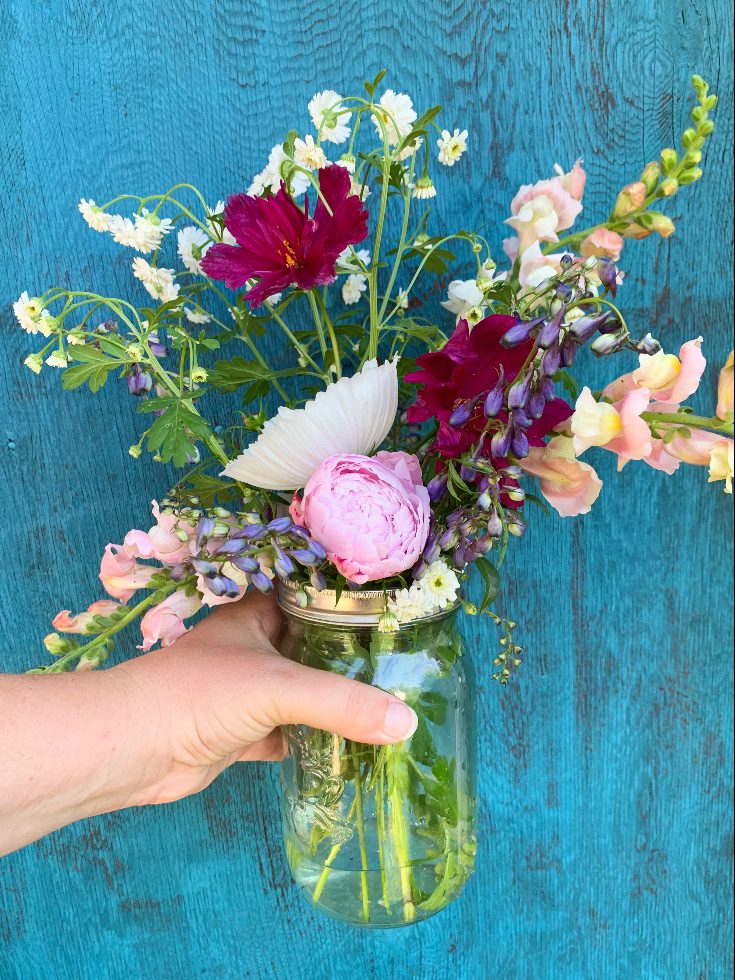 Bouquet in a mason jar infant of a blue door.