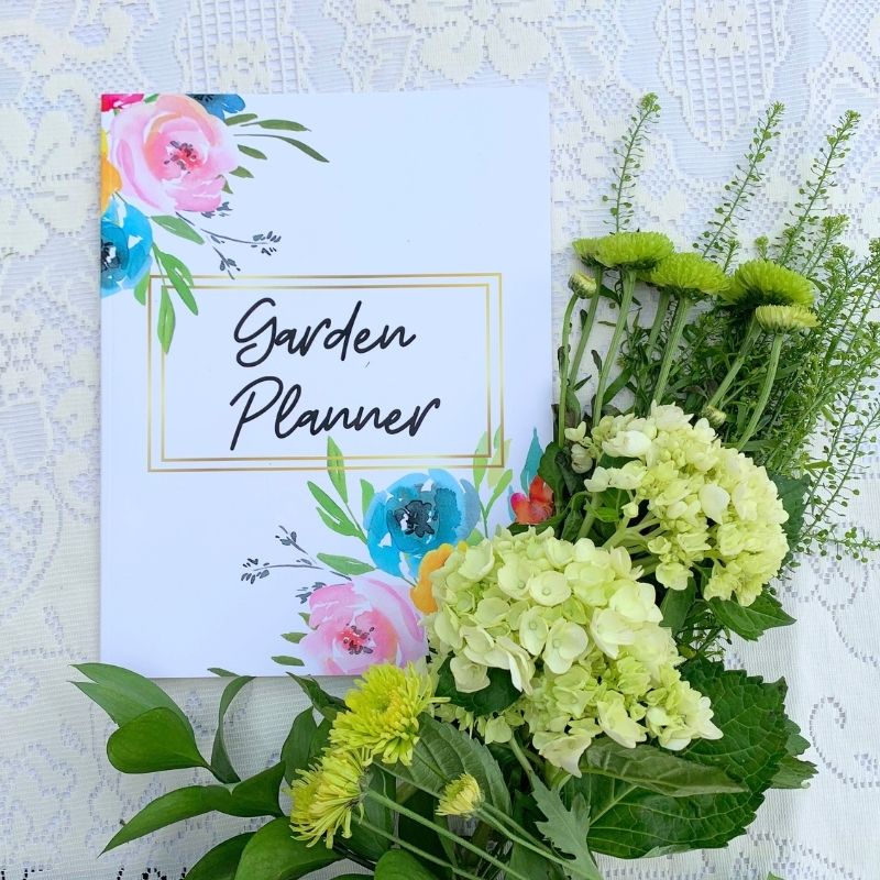 Garden planner with light green and cream flowers beside it.